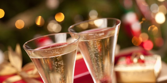 Sparkling Champagne Flutes and Gifts in Front of Decorations and Lights.