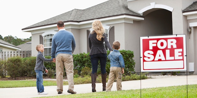 A family stands before a home for sale.
