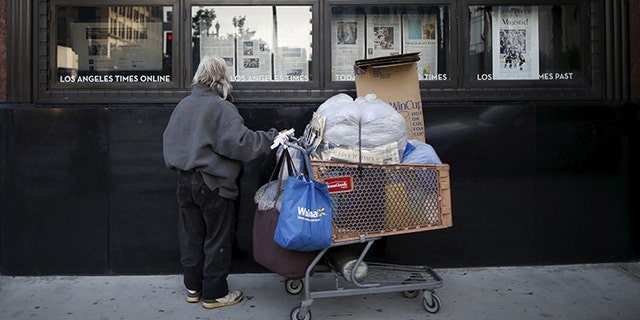 A homeless man reads the Los Angeles Times in the window of the building of Los Angeles Times newspaper, in Los Angeles, California