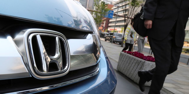 In this April 25, 2014 file photo, a man walks past a Honda on display at Honda Motor Co. headquarters in Tokyo.