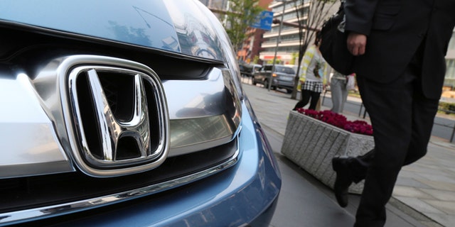 In this April 25, 2014 file photo, a man walks past a Honda on display at Honda Motor Co. headquarters in Tokyo.