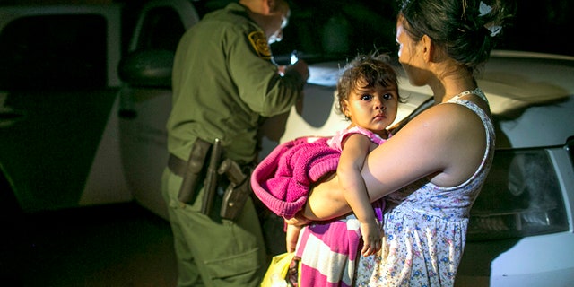 July 3, 2014: Flor Garcia, 19, of Honduras, holds her 1-year-old daughter, Flor Fernandez, after they turned themselves over to Customs and Border Protection Services agents after crossing the Rio Grande from Mexico near McAllen, Texas.