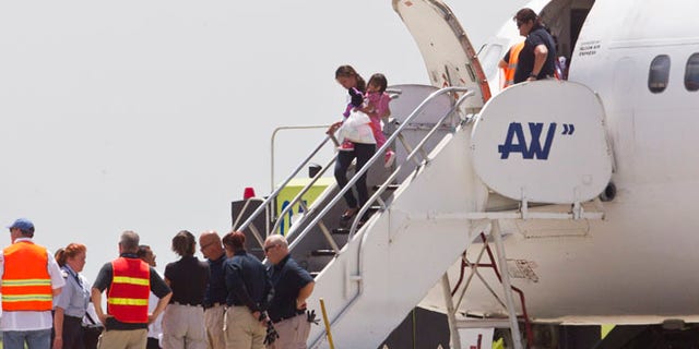 July 18, 2014: Immigration and Custom officials standby as a woman and child, who were deported from the United States, deplane at the San Pedro Sula airport, in Honduras. (AP)