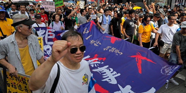 Protesters carry a banner with Chinese words "End the one party rule in China" as thousands of protesters march along a downtown street during an annual pro-democracy protest in Hong Kong Sunday, July 1, 2018.
