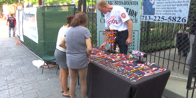 Volunteers from the Church of the Annunciation sell Astros-themed rosary beads two hours before home games.