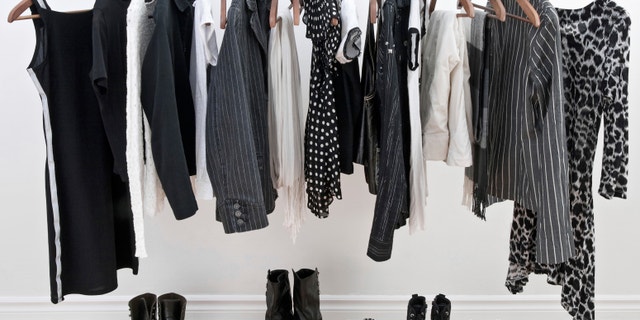 Female black and white clothes on a pole and shoes on a wooden floor.