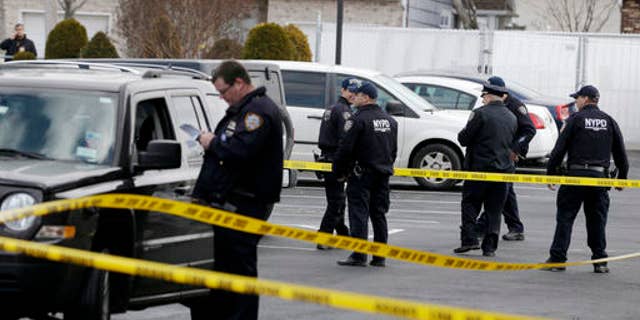 Police officers stand in the parking lot of a Ramada Inn, where authorities say a man stabbed a woman and her children in the Staten Island borough of New York, Wednesday, Feb. 10, 2016. (AP Photo/Seth Wenig)