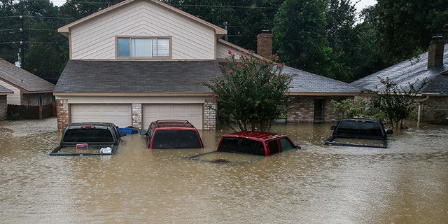 FILE - In this Aug. 29, 2017, file photo, trucks are submerged on Pine Cliff Drive in Houston during heavy rainfall from Tropical Storm Harvey. Few American cities depend on cars as much as Houston, and Harvey's record rainfall left flooded roads and neighborhoods with cars submerged and, in most cases, impossible to salvage. (Michael Ciaglo/Houston Chronicle via AP)