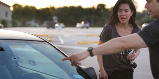 Alan Wakim shows his wife, Jennifer Molleda, where two bullets entered his windshield.