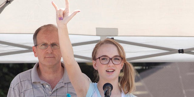 July 12, 2014: Cassidy Stay stands with her grandfather Roger Lyon (L) as she addresses the crowd during a memorial service for members of the Stay family who were murdered in their home Wednesday, in Spring, Texas.