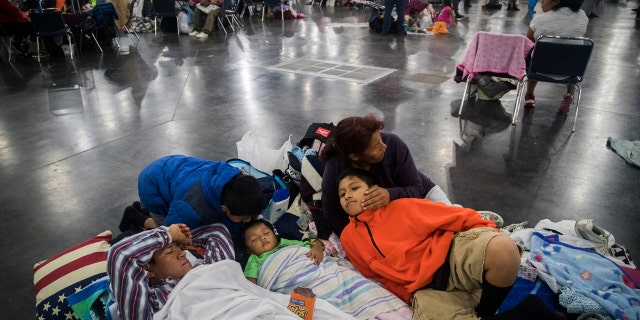 Oscar Galindo, Donato Galindo, 2, Oscar Galindo, 11, Andre Galindo, 9, and Maria Rodriguez relax while taking shelter at the George R Brown Convention Center on Monday, Aug. 28, 2017, in Houston.