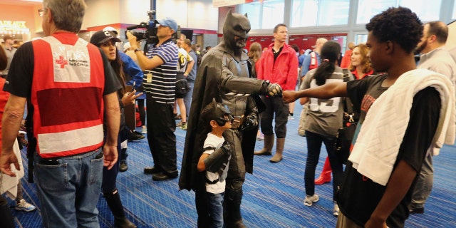 A man dressed as Batman shakes hands with people as they arrive at the Red Cross shelter at the George Brown Convention Center in Houston, Monday, Aug. 28, 2017, in the wake of Tropical Storm Harvey.