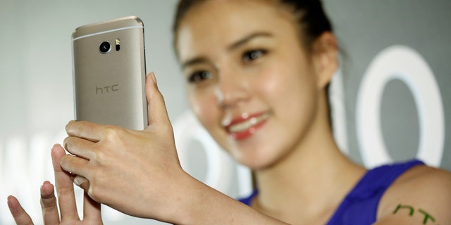 A model poses for photographs with HTC 10, an Android-based smartphone, during its launch event in Taitung, Taiwan April 12, 2016. (REUTERS/Tyrone Siu)