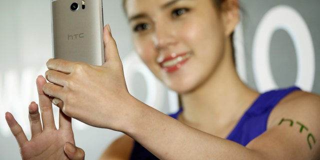A model poses for photographs with HTC 10, an Android-based smartphone, during its launch event in Taitung, Taiwan April 12, 2016. (REUTERS/Tyrone Siu)