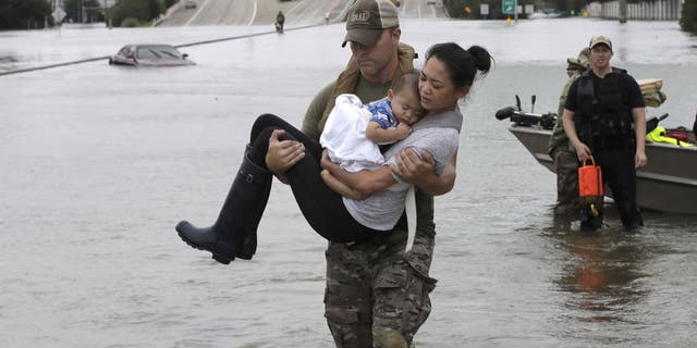 In an image that went viral online, Houston Police SWAT Officer Daryl Hudeck carried a Houston mom and her sleeping baby through knee-deep floodwaters in southwest Houston.