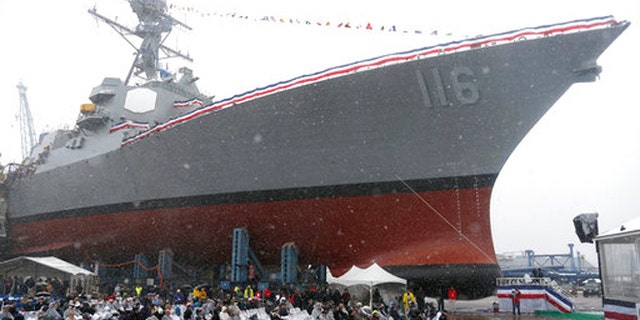 The future USS Thomas Hudner, a U.S. Navy destroyer named after Korean War veteran Thomas Hudner, looms over the audience during a christening ceremony at Bath Iron Works in Bath, Maine, Saturday.