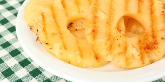 Juicy grilled pineapple on plate on table close-up