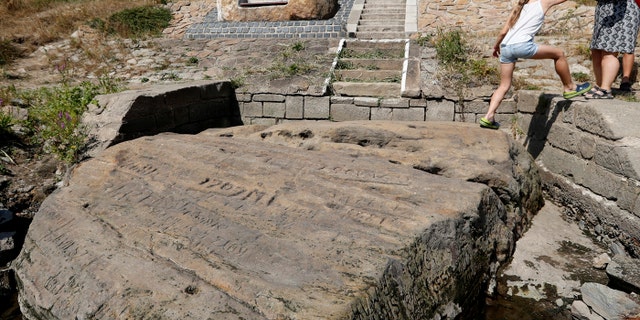 People visit one of the so called "hunger stones" exposed by the low level of water in the Elbe river in Decin, Czech Republic, Thurs., Aug. 23, 2018
