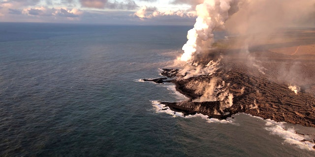 This photo provided by the U.S. Geological Survey shows where lava from Kilauea Volcano is entering the ocean and the resulting laze plume where lava is entering the sea at Kapoho on the island of Hawaii at dawn Wednesday, June 13, 2018.