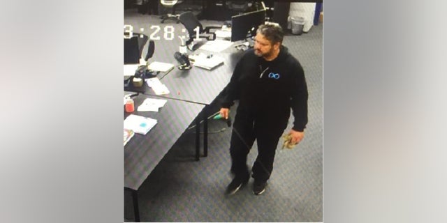 The purported surveillance camera image allegedly showing Afshin Pishevar approaching BamBrogan’s desk with a noose coiled in his left hand (image from lawsuit).