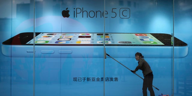 A worker cleans glass in front of an iPhone 5C advertisement at an apple store in Kunming, Yunnan province, in this October 27, 2013 file picture.