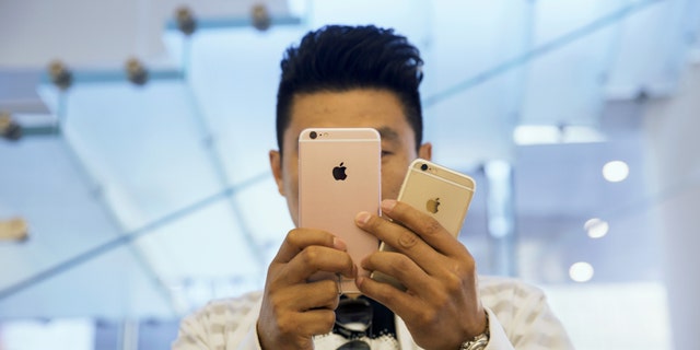 A man takes pictures as Apple iPhone 6s and 6s Plus go on sale at an Apple Store in Beijing, China Sept. 25, 2015.