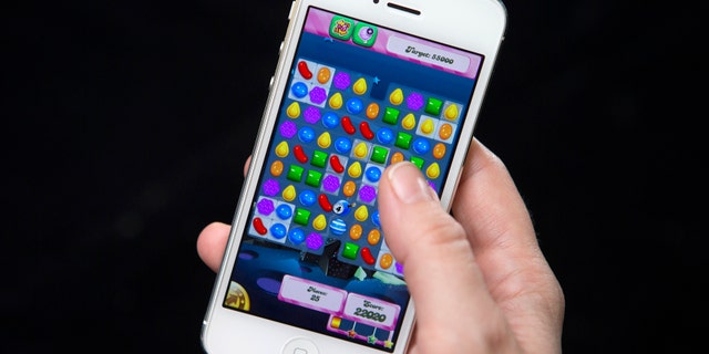 A woman poses for a photo illustration with an iPhone as she plays Candy Crush in New York February 18, 2014. King, the Swedish firm behind hit mobile phone game Candy Crush Saga, is planning a U.S. stock market debut which some analysts think could value it at more than $5 billion and herald a flurry of technology company listings this year. REUTERS/Carlo Allegri (UNITED STATES - Tags: BUSINESS SCIENCE TECHNOLOGY) - RTX19278