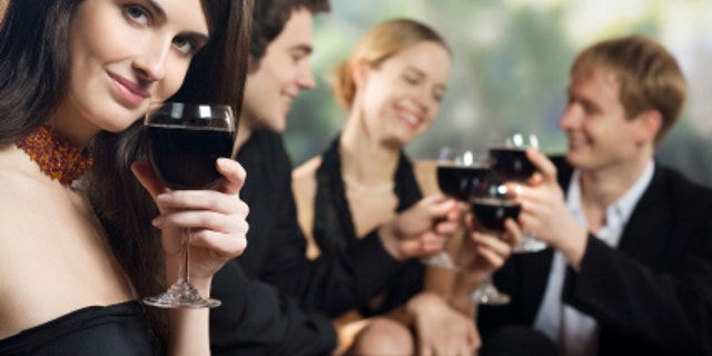 Two young couples with red-wine glasses at celebration or party