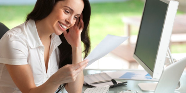 Attractive woman smiling reading a document at her desk