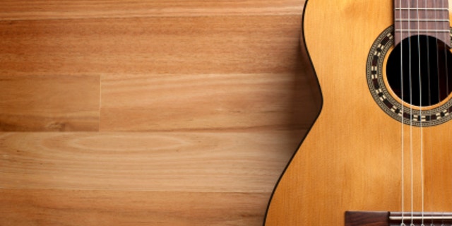Acoustic guitar with wood background and copy space.