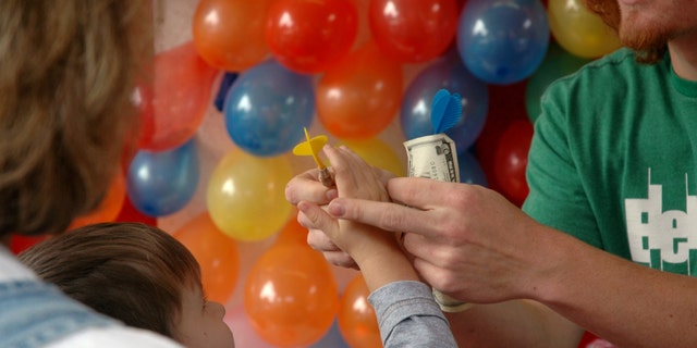 A little boy pays the money for a chance at a prize.
