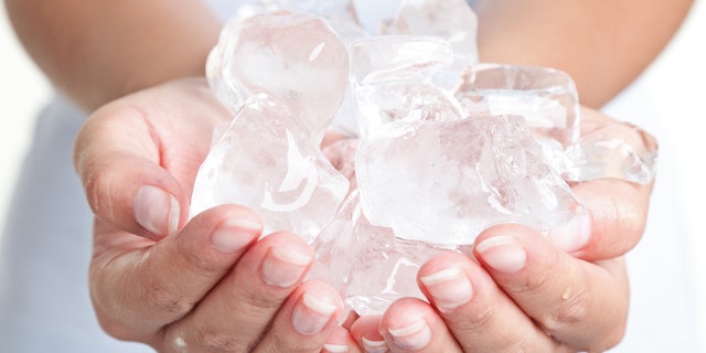 Ice cold hands. Woman hands holding ice cubes - closeup.