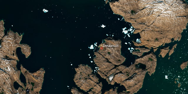 The satellite image, which was captured by Sentinel-2A on July 9, 2018, provided by European Space Agency esa on Tuesday, July 18, 2018 shows a huge iceberg perilously close to the village of Innaarsuit on the west coast of Greenland. If the berg breaks apart, waves resulting from the falling ice could wash away parts of the village. (esa via AP)