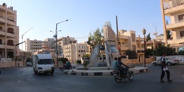 Men ride motorcycles calmly through the streets of Idlib, Syria