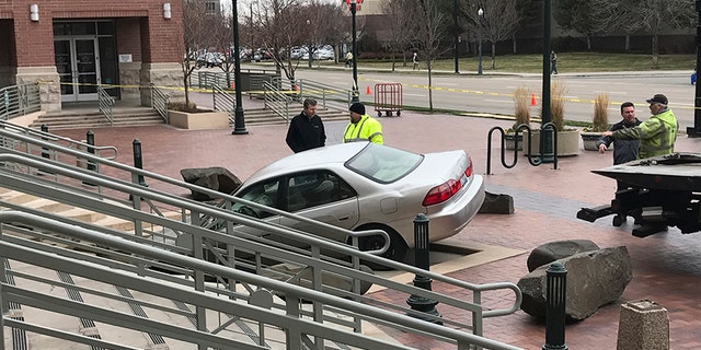 Rescue crews remove a vehicle crashed earlier intentionally into the Ada County Courthouse fountain in Boise, Idaho, Sunday, Dec. 10, 2017. Authorities say Jonathan Locksmith upset with the court system tried to crash a car into the courthouse in the state's capital city Sunday morning, spinning his vehicle around in a "doughnut" before landing it in the fountain downtown Boise. Locksmith was arrested on a misdemeanor reckless driving charge. (Katy Moeller/The Idaho Statesman via AP)