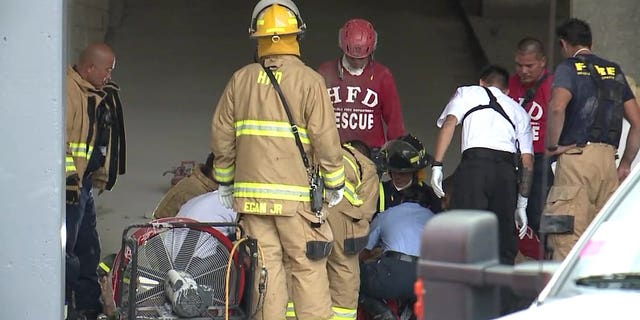 Emergency crews treat a man who was freed from between two buildings in Honolulu, March 23, 2018.