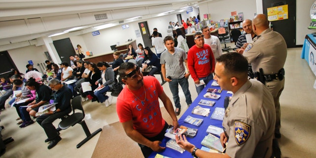 California Highway Patrol officers Armando Garcia, right, and Ray Patton explain to immigrants the process of getting a drivers license during an information session at the Mexican Consulate, in San Diego.