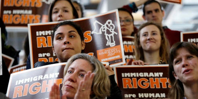 Demonstrators holding immigrant rights signs look on at a post-election event of elected officials and community leaders Wednesday, Nov. 9, 2016, at City Hall in Seattle. Seattle Mayor Ed Murray said the country had elected a leader who has "demonstrated outright misogyny" and displayed "racism and authoritarian tendencies." Murray said despite the views held by President-elect Donald Trump, Seattle would remain a welcoming city for immigrants, minorities and others. (AP Photo/Elaine Thompson)