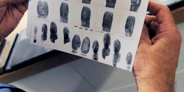 In this July 26, 2010 photo,Senior Deputy Jerry Anttila looks at a set of fingerprints for an unidentified suspect during the booking process at the Arapahoe County Justice Center in Centennial, Colo. (AP)