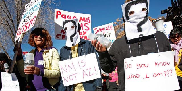 From right, Irvin Pacheco and Isiah Becerra wear masks and join protesters at the Capitol on Monday, Feb. 7, 2011 in Santa Fe. (AP)