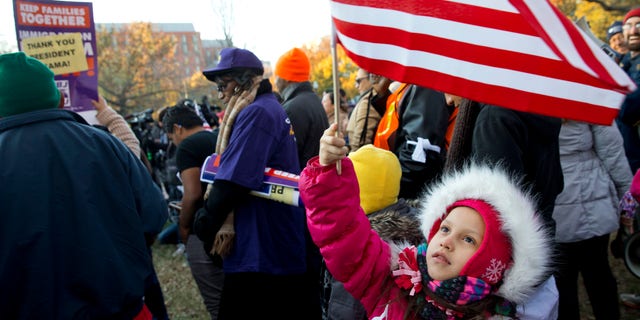 Nov. 21, 2014: Joselyn Vargas, 7, of Hyattsville, Md., waves a U.S. flag during a rally in Lafayette Park across from the White House in Washington
