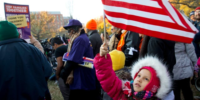 Nov. 21, 2014: Joselyn Vargas, 7, of Hyattsville, Md., waves a U.S. flag during a rally in Lafayette Park across from the White House in Washington