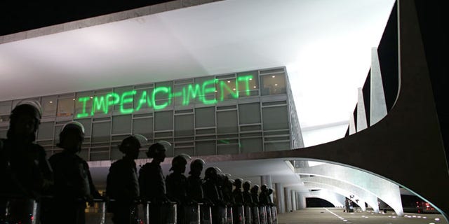 FILE - In this March 21, 2016 file photo, soldiers stand guard outside Planalto presidential palace where protesters projected the word "Impeachment" on the building, as they call for the impeachment of Brazil's President Dilma Rousseff in Brasilia, Brazil. On Thursday, the Senate will begin the final phase of Rousseff's trial for allegedly breaking fiscal rules in her management of the federal budget. Several days of deliberations, including an address by Rousseff herself, will culminate in a final vote early next week. (AP Photo/Eraldo Peres, File)