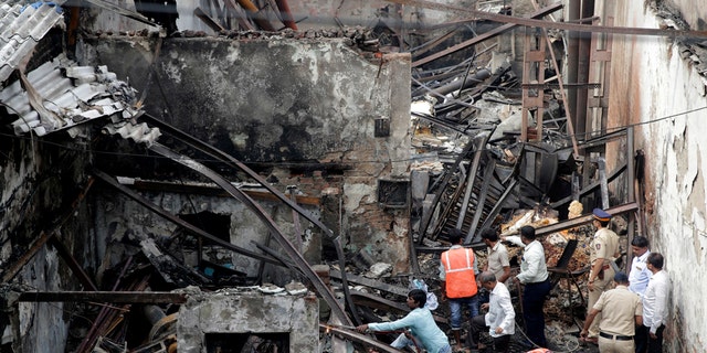 Indian fire officials inspect the burnt down shop in Mumbai, Monday, Dec. 18, 2017.