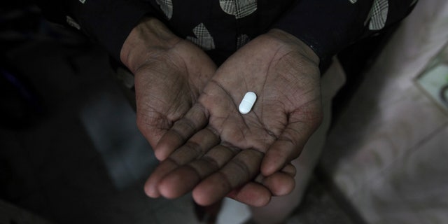 Seema (R), 33, displays an anti-retroviral drug used to treat HIV/AIDS, inside his residence in New Delhi. REUTERS/Adnan Abidi