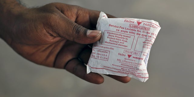 A man shows a packet of government-supplied 'Nirodh' condoms after collecting it from a distribution center at a hospital in New Delhi April 1, 2015. REUTERS/Adnan Abidi