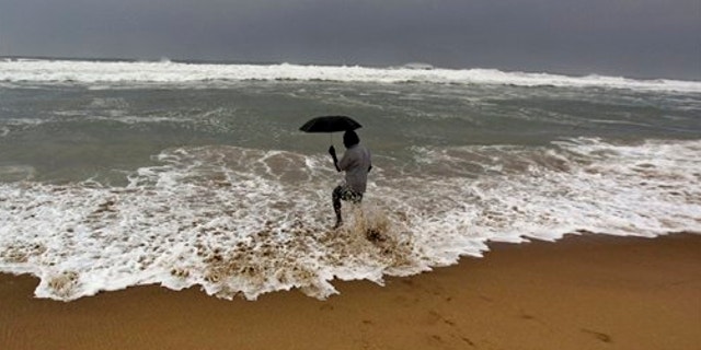 Oct. 11, 2013: An Indian man holds on to his umbrella as he fishes in high tide waves at Gopalpur beach, in Ganjam district, 136 miles away from the eastern Indian city of Bhubaneswar, India.