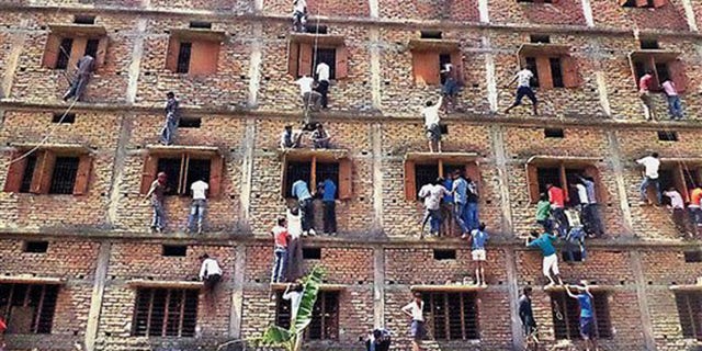 In this file photo, Indians climb the wall of a building to help students appearing in an examination in Hajipur, in the eastern Indian state of Bihar.