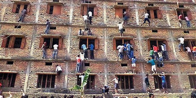 In this file photo, Indians climb the wall of a building to help students appearing in an examination in Hajipur, in the eastern Indian state of Bihar.