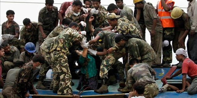 Indian rescue workers and security personnel bring out the body of a woman from a carriage at the site of a train crash near Sardiha, West Bengal state, about 150 kilometers (90 miles) west of Calcutta, India, early Friday, May 28, 2010. The overnight passenger train was derailed by an explosion then hit by another train early Friday as it traveled through a rebel stronghold of eastern India, officials said. A top government official said a number of people have been killed and scores injured. (AP Photo/Bikas Das)
